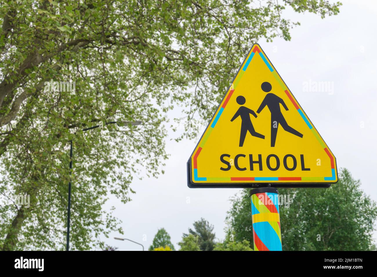 Panneau de signalisation pour le passage à niveau des écoles. Triangle jaune d'avertissement pour la zone scolaire signalisation routière aux pays-Bas, arbres en arrière-plan Banque D'Images