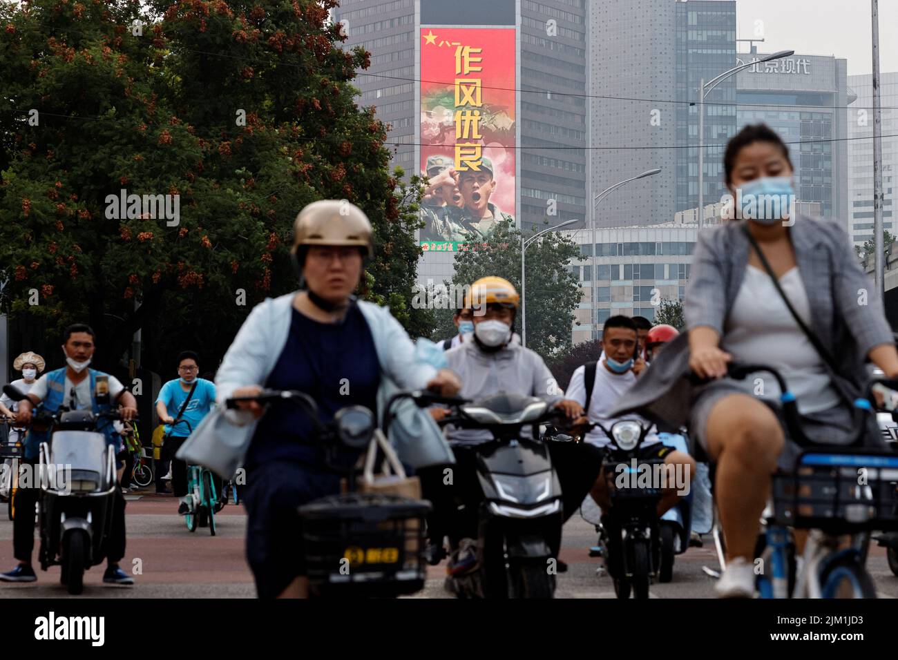 Les gens sont à bord d'un véhicule près d'un écran affichant une image de l'Armée populaire de libération chinoise (ALP) à Pékin, en Chine 4 août 2022. REUTERS/Thomas Peter Banque D'Images