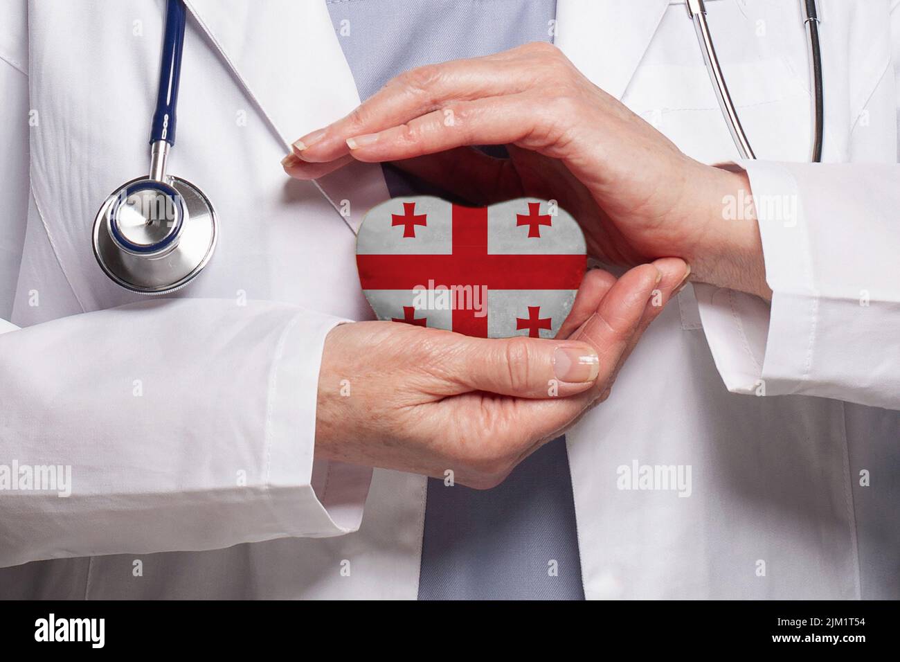 Médecin géorgien tenant le coeur avec le drapeau de fond de la Géorgie. Concept de santé, de charité, d'assurance et de médecine Banque D'Images