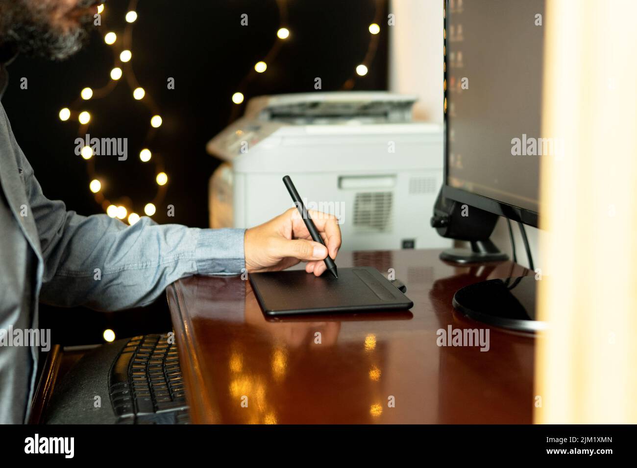 Jeune graphiste gaucher assis dans son espace de travail à l'aide d'une tablette graphique numérique. Professionnel. Freelance. Banque D'Images