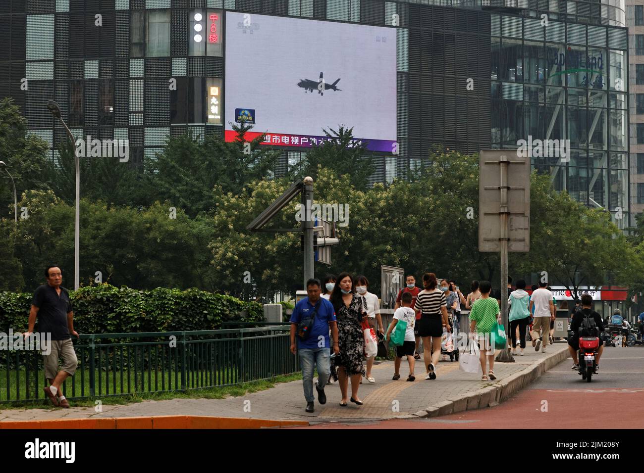 Des piétons marchent devant un écran géant diffusant un reportage sur les exercices militaires de l'Armée populaire de libération chinoise (ALP) autour de Taïwan, à Pékin, en Chine 4 août 2022. REUTERS/Thomas Peter Banque D'Images