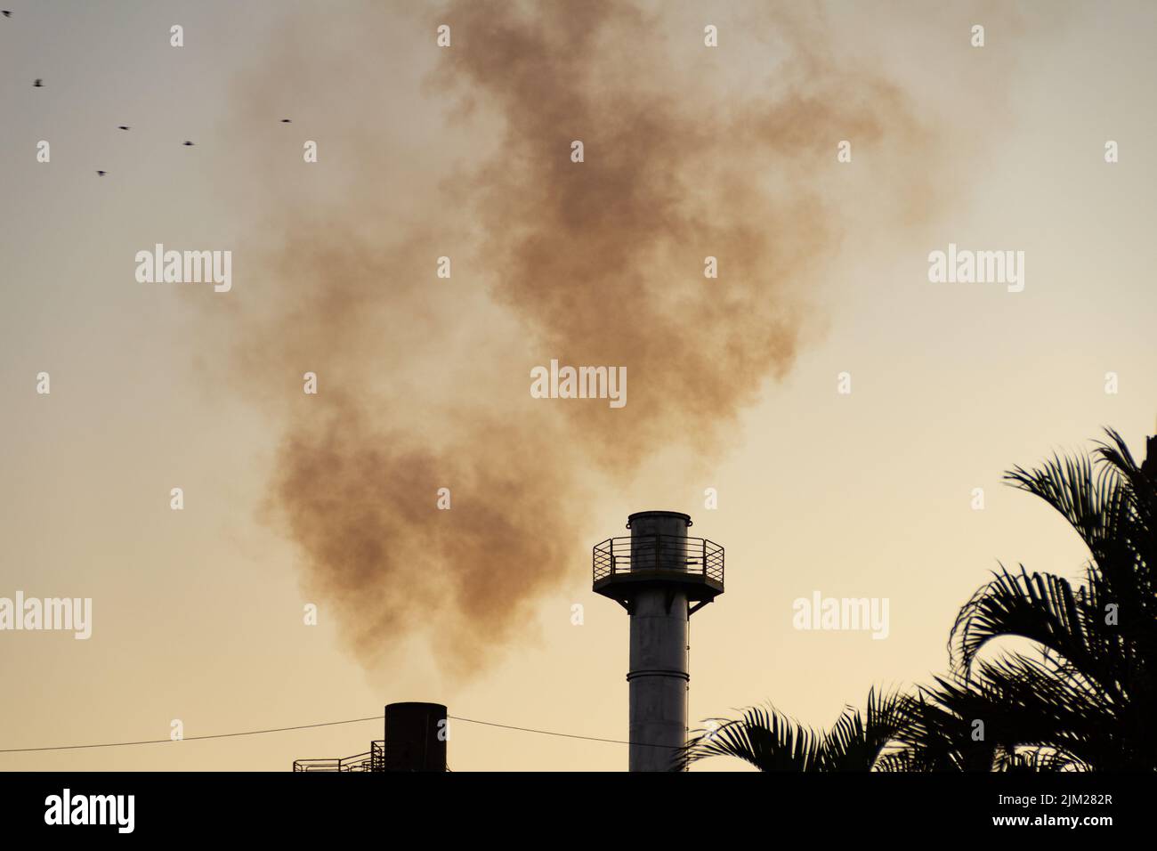 Goiania, Goiás, Brésil – 04 août 2022: Fumée provenant de deux cheminées d'une usine. Pollution de fumée d'usine avec le ciel en arrière-plan. Banque D'Images