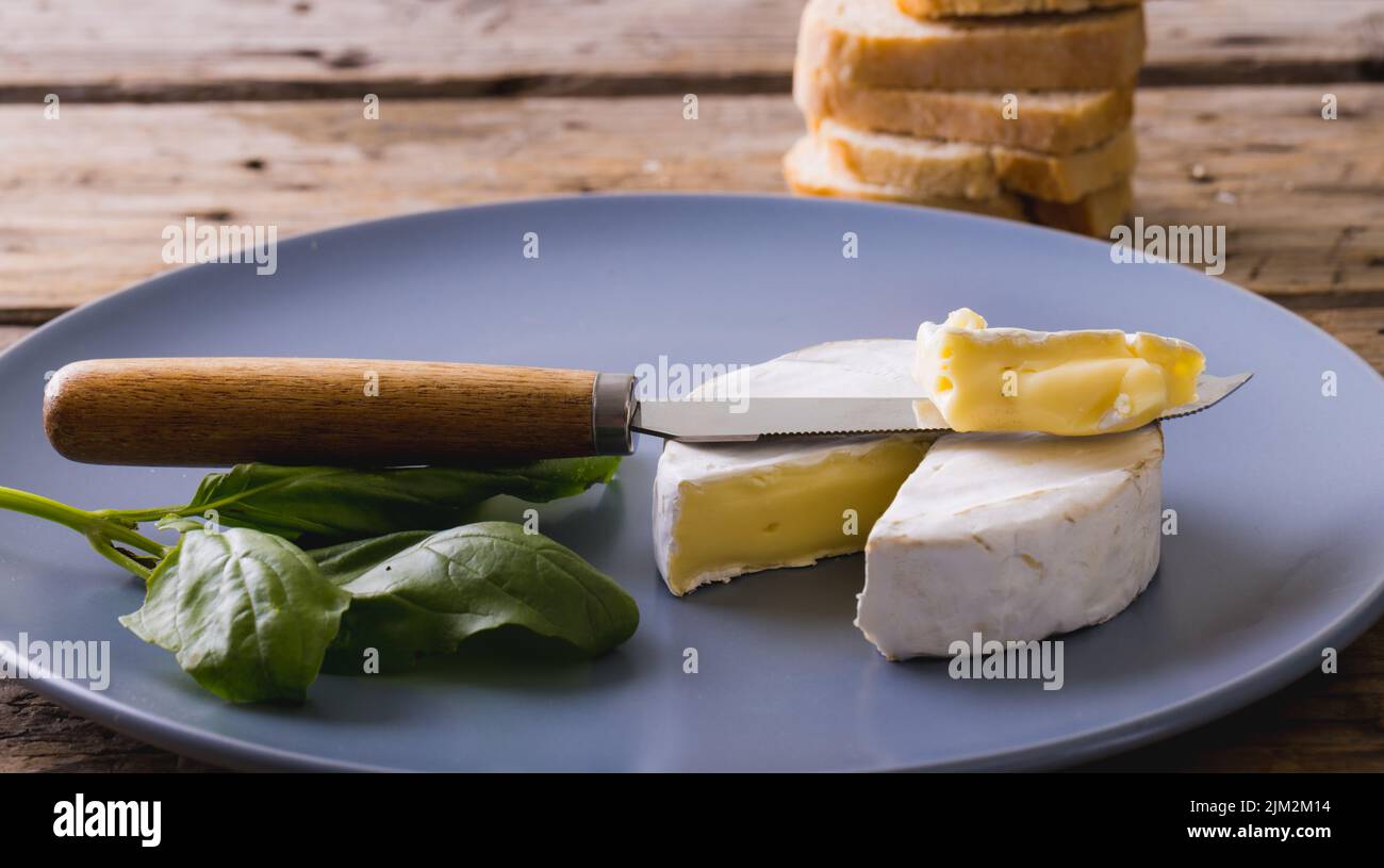Gros plan du brie avec herbe et couteau dans l'assiette sur la table, espace de copie Banque D'Images