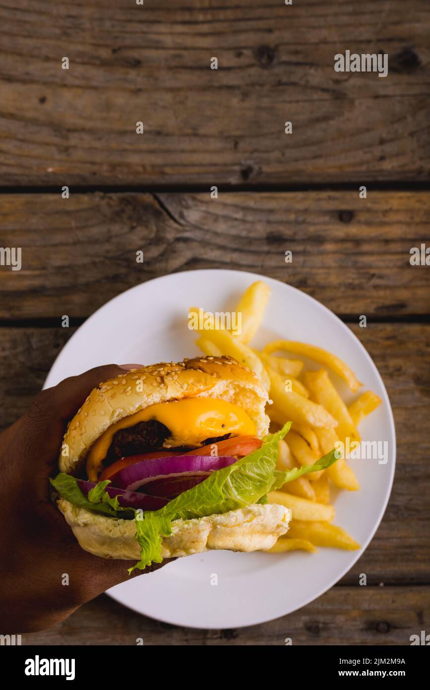 Les mains de l'homme afro-américain ont été rognées avec un hamburger tandis que les frites sont dans l'assiette, dans l'espace réservé aux copies Banque D'Images