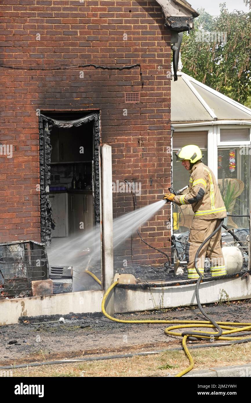 Feu de maison entre la clôture de limite en bois et le mur latéral pare-feu amortissement feu de bois mis sous contrôle charred UPVC cuisine cadre de porte Essex Angleterre Royaume-Uni Banque D'Images