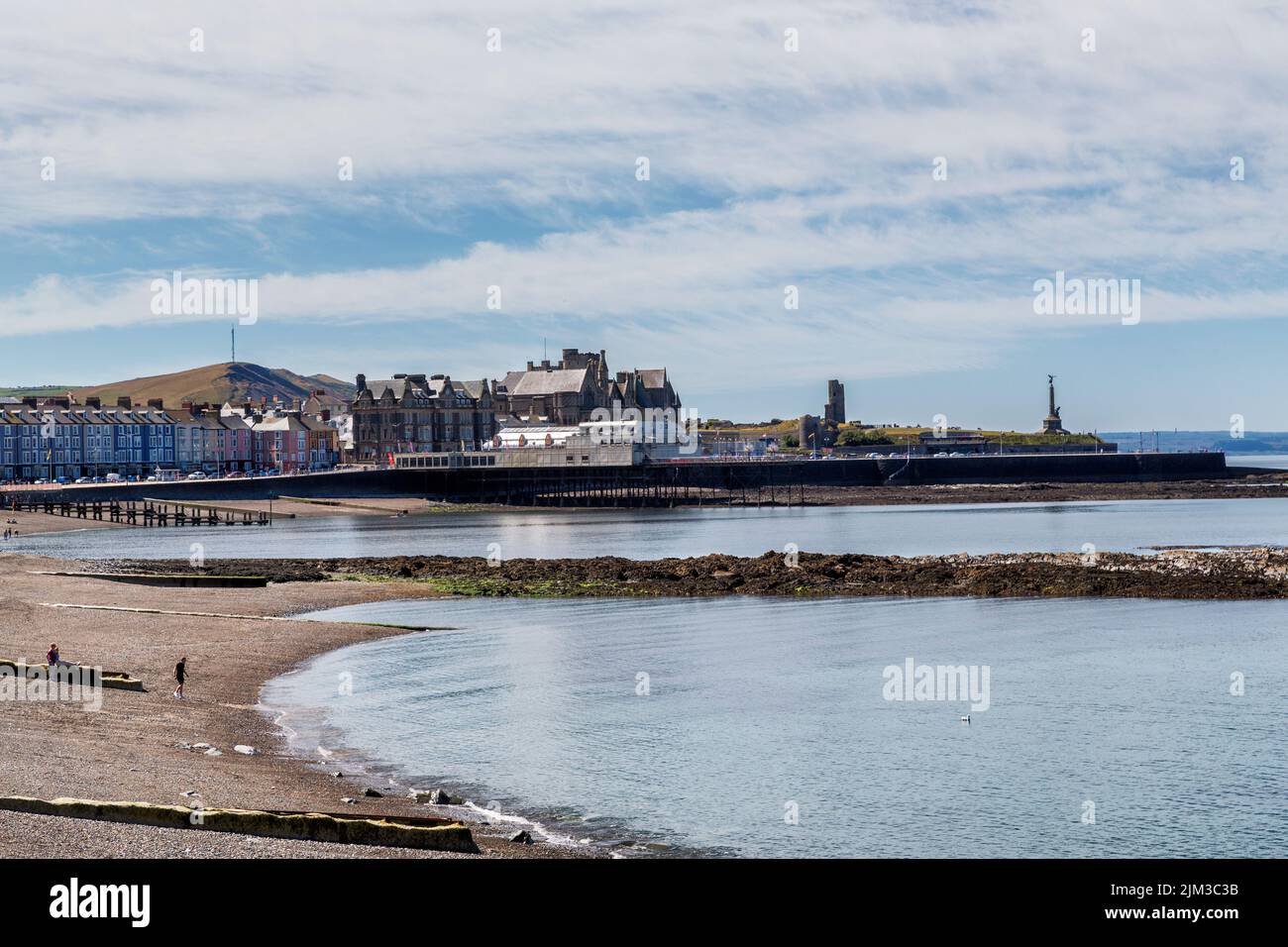 Vue sur la plage de galets et la jetée de Cardigan Bay, Aberystwyth. Le Vieux Collège, les ruines du château et le mémorial de guerre peuvent également être vus. Banque D'Images