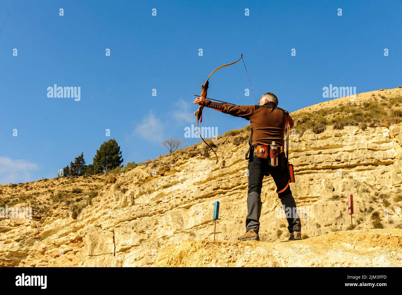 Homme avec arc et flèche pratiquant le tir à l'arc dans le parc. Banque D'Images