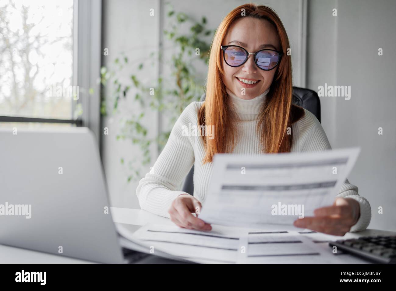 Une femme mûre heureuse avec des documents ou des factures dans un bureau Banque D'Images