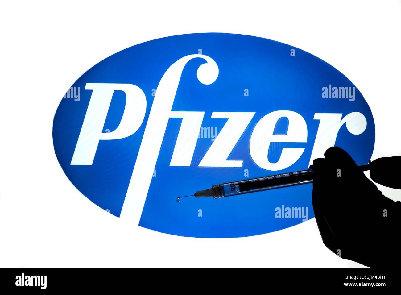 Logo de la société pharmaceutique Pfizer avec aiguille hypodermique et seringue à main Banque D'Images