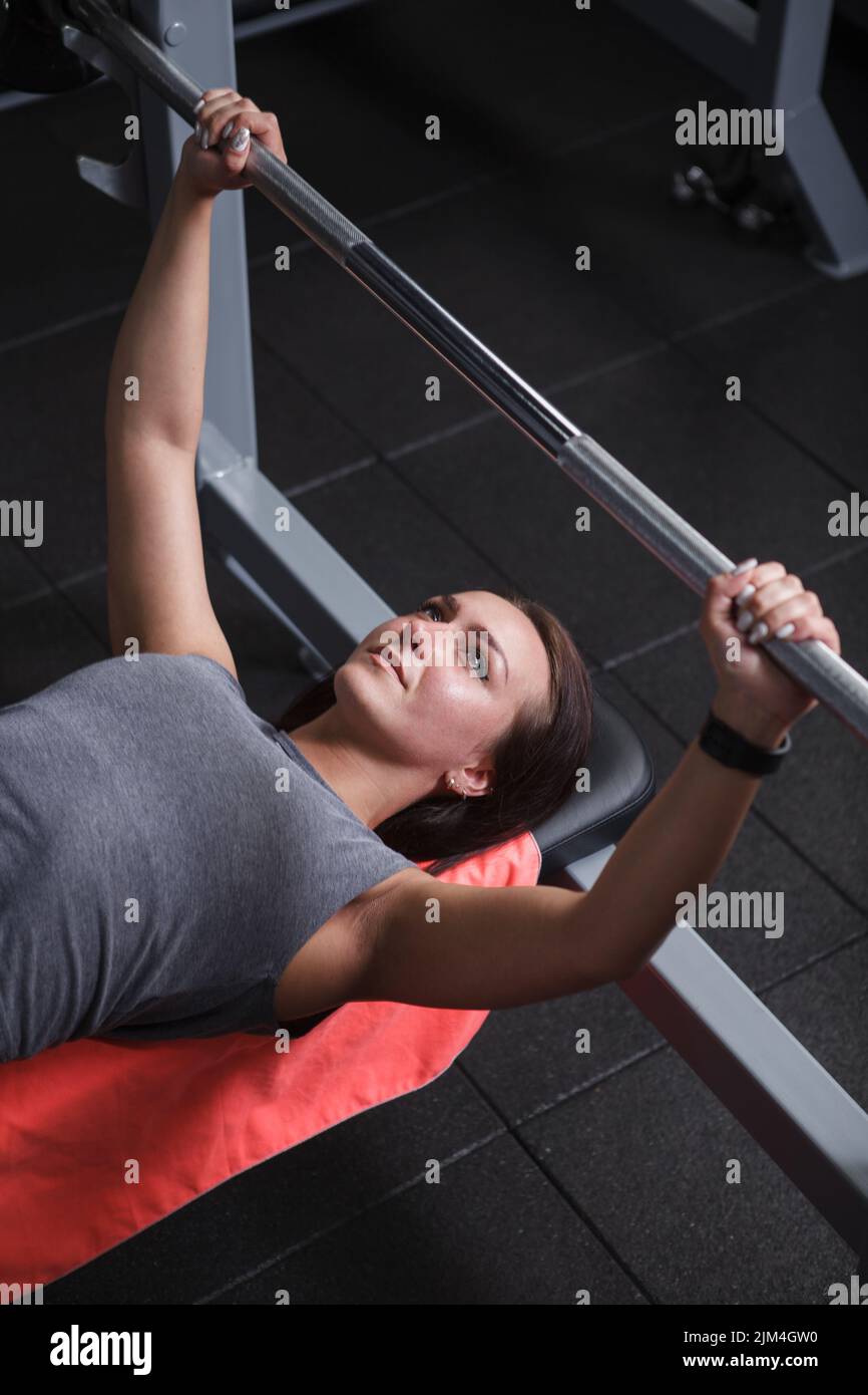 Photo verticale en haut d'une belle athlète féminine se concentrant avant l'entraînement de presse de banc de barbell Banque D'Images