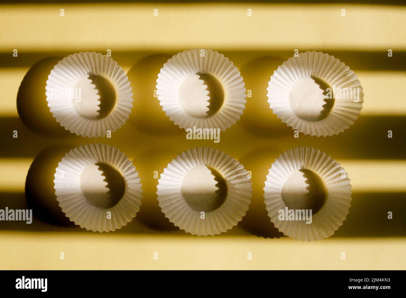 vider les gobelets en papier de cuisson. boîtes en papier blanc à biscuits isolées sur fond jaune avec ombre Banque D'Images