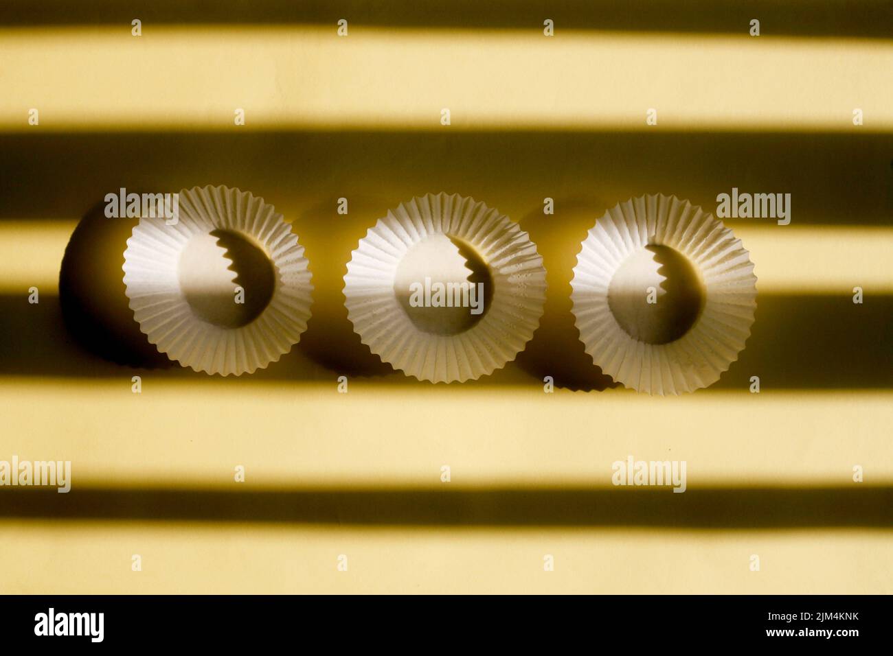 vider les gobelets en papier de cuisson. boîtes en papier blanc à biscuits isolées sur fond jaune avec ombre Banque D'Images