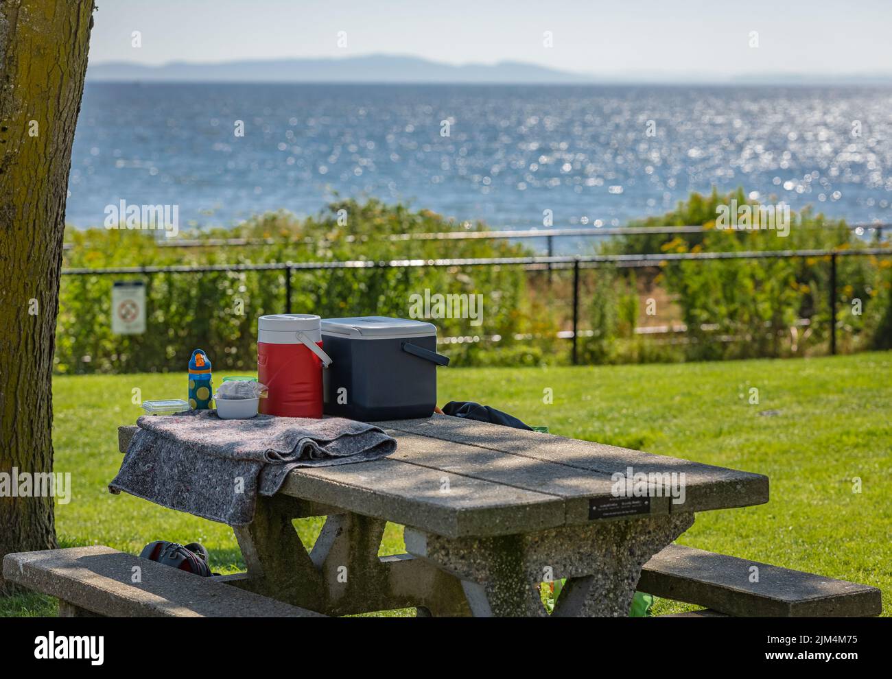 Table de pique-nique avec boîtes et paniers de nourriture pour le pique-nique en plein air dans un parc au fond de la mer et des montagnes. White Rock C.-B. Canada. Rue Banque D'Images