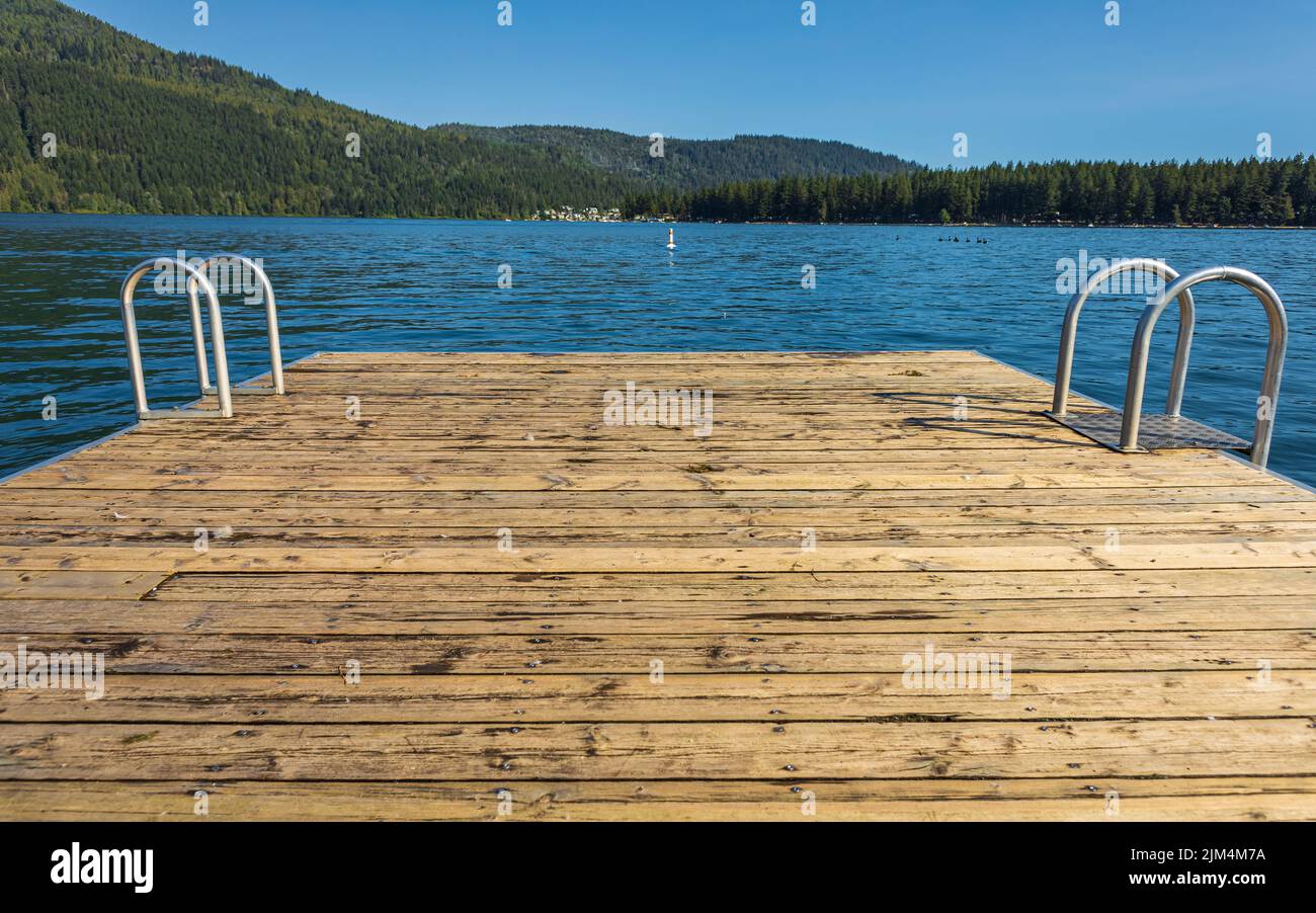 Jetée en bois avec échelle en métal dans la mer, le lac, l'eau. Quai de baignade avec échelle en métal sur le lac bleu calme à la journée ensoleillée sur la station idyllique au culte Banque D'Images