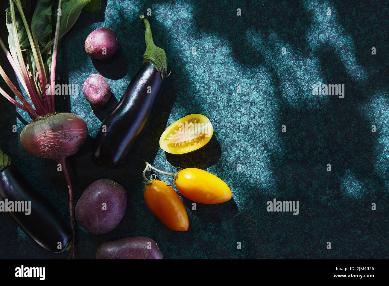 Légumes de saison - tomates jaunes, aubergines, betteraves sous des ombres dures tendance sur fond réfléchissant. Problème écologique. Ombres dures. Copie s Banque D'Images