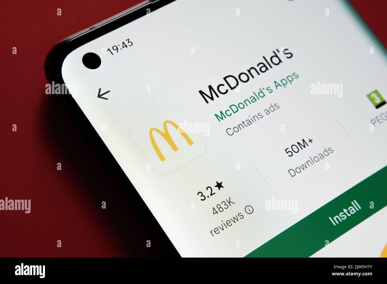 Application McDonald's vue dans Google Play Store sur l'écran du smartphone placé sur fond rouge. Gros plan avec mise au point sélective. Stafford, United King Banque D'Images