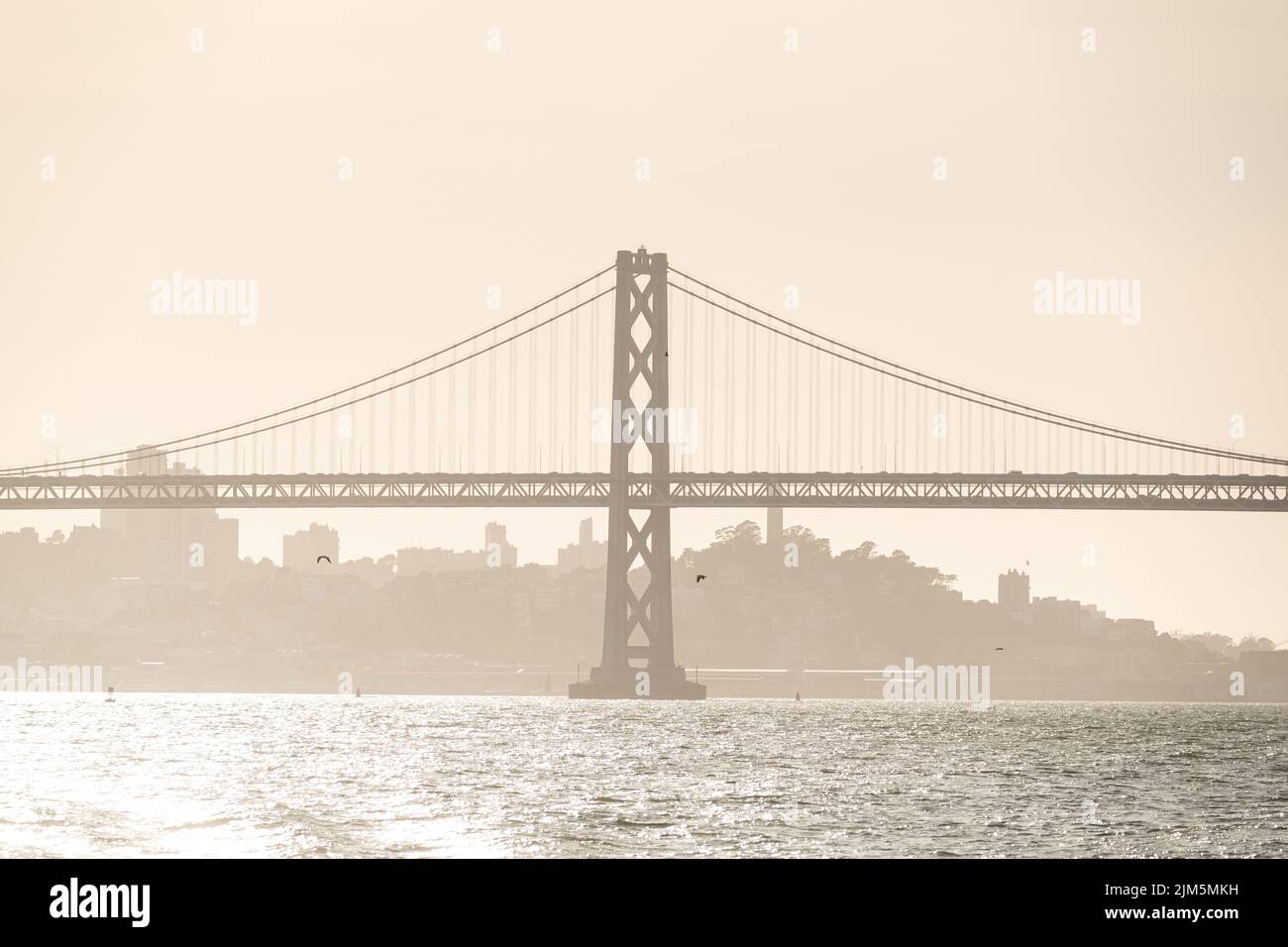 Un téléobjectif du San Francisco-Oakland Bay Bridge au coucher du soleil avec le San Francisco Skyline en arrière-plan. Banque D'Images