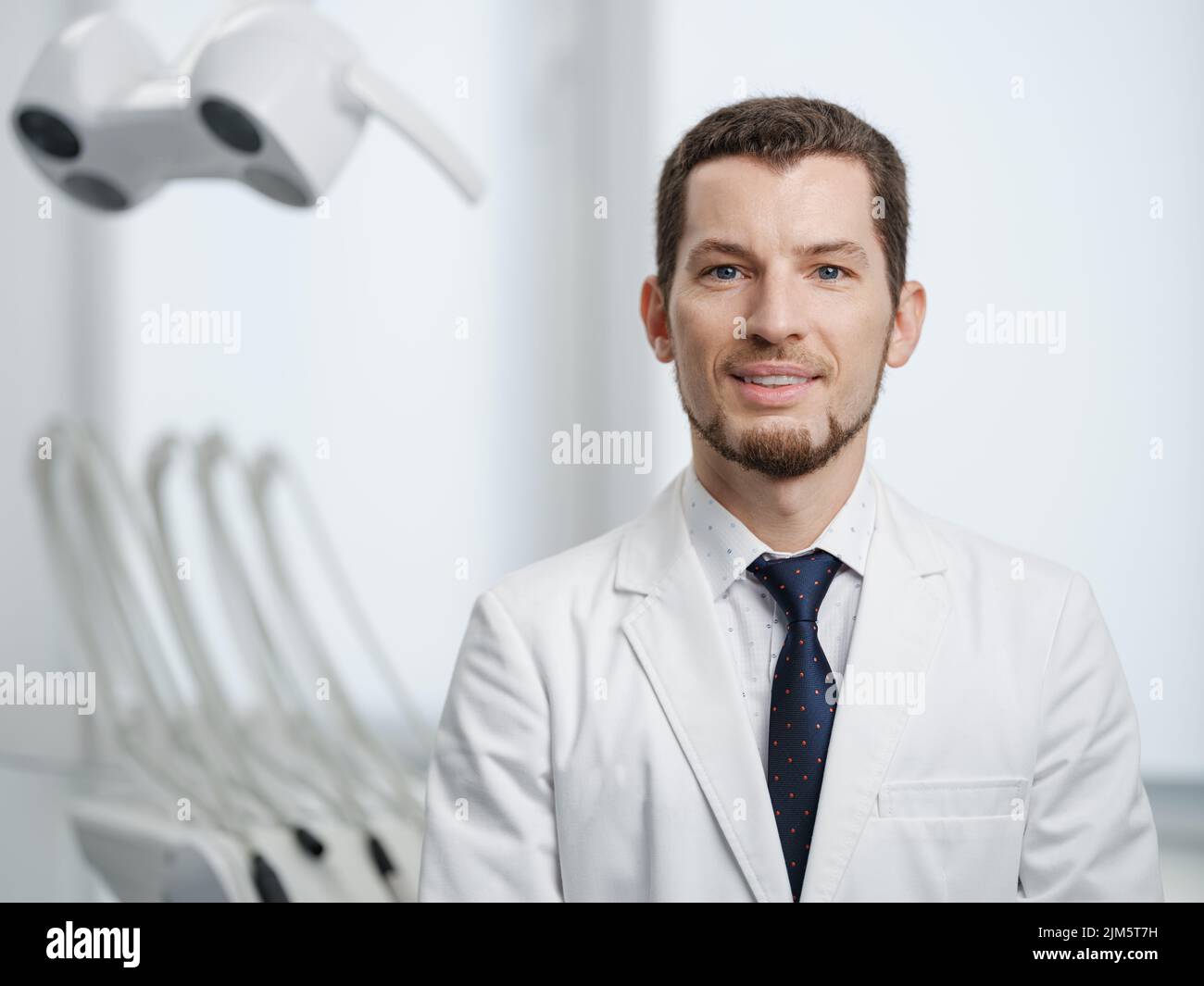 Gros plan portrait d'un dentiste souriant en blouse de laboratoire blanche regardant l'appareil photo Banque D'Images