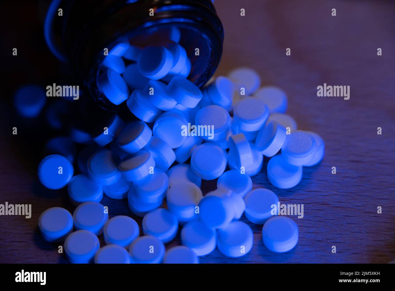 Pilules blanches sous lumière bleue. Médicaments et suppléments de santé. Flacons pharmaceutiques médicaux pour les infections virales. Banque D'Images