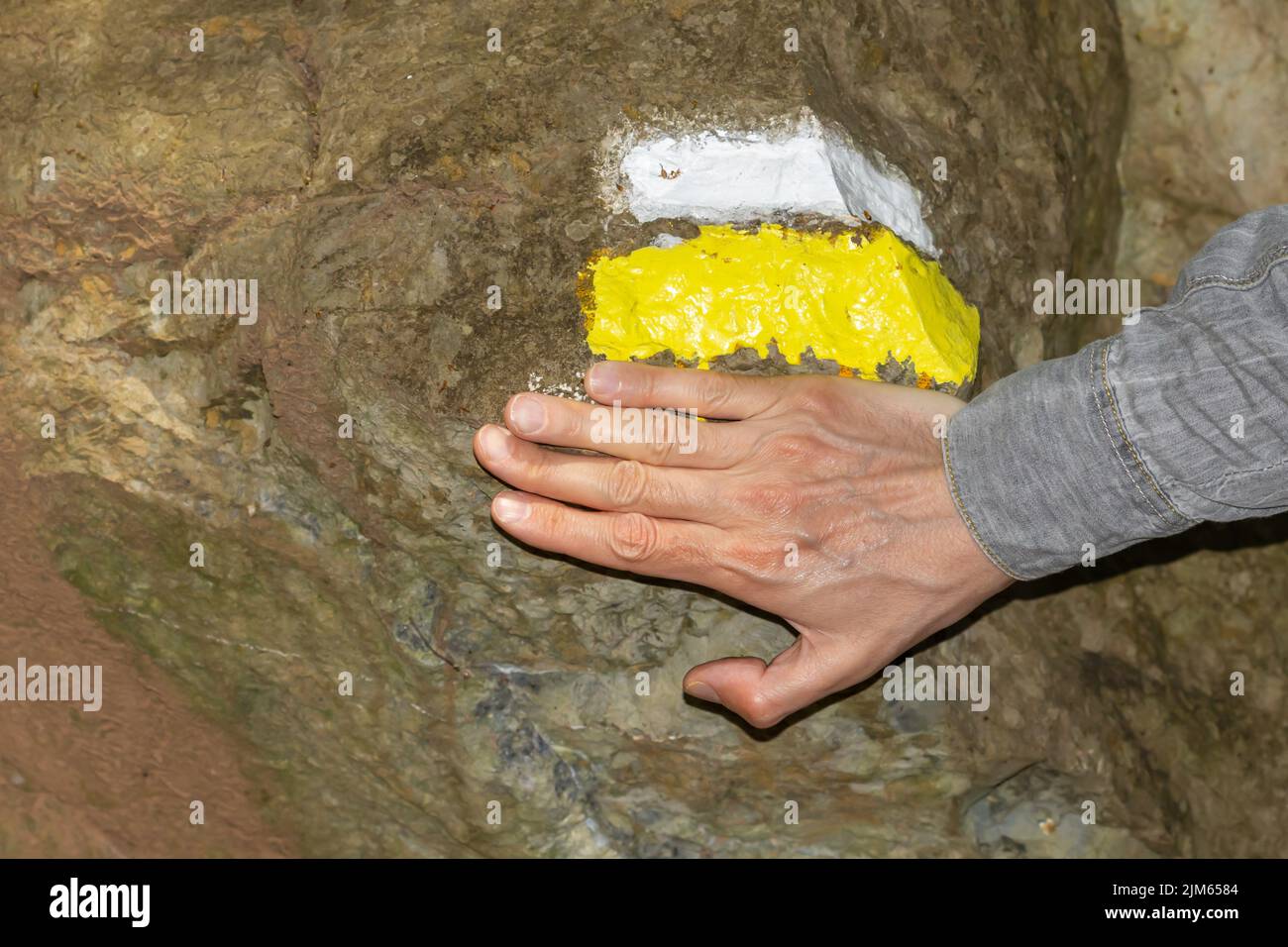 Panneau de randonnée peint sur un rocher marquant la direction du chemin avec la main d'homme non reconnaissable. Banque D'Images
