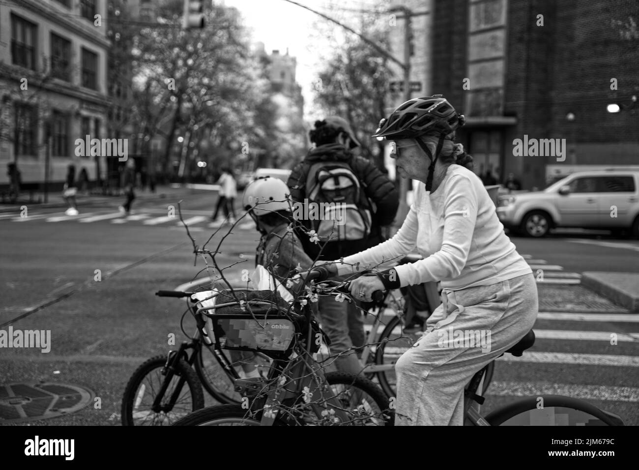 Un gros plan en échelle de gris d'une femme âgée qui descend la rue à vélo. New York, États-Unis. Banque D'Images