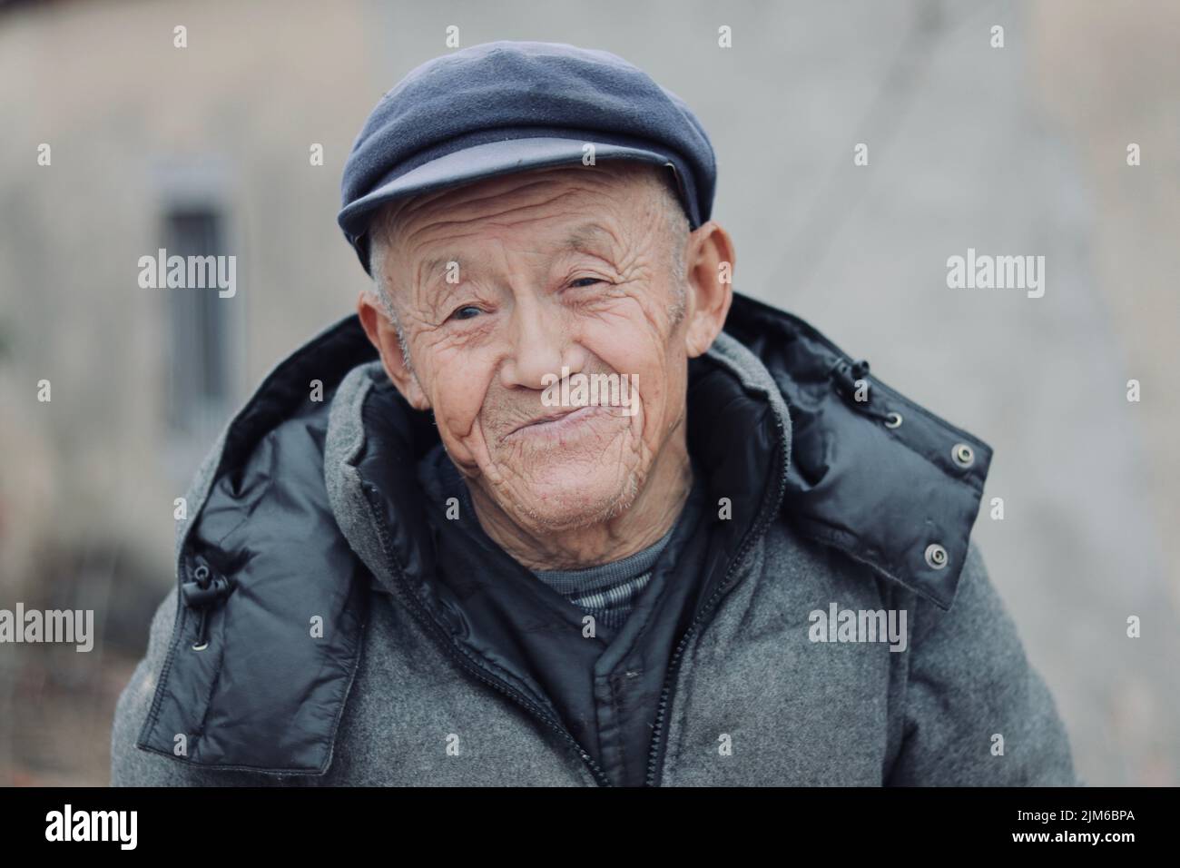 Un homme âgé avec un sourire doux portant un chapeau et un manteau d'hiver Banque D'Images