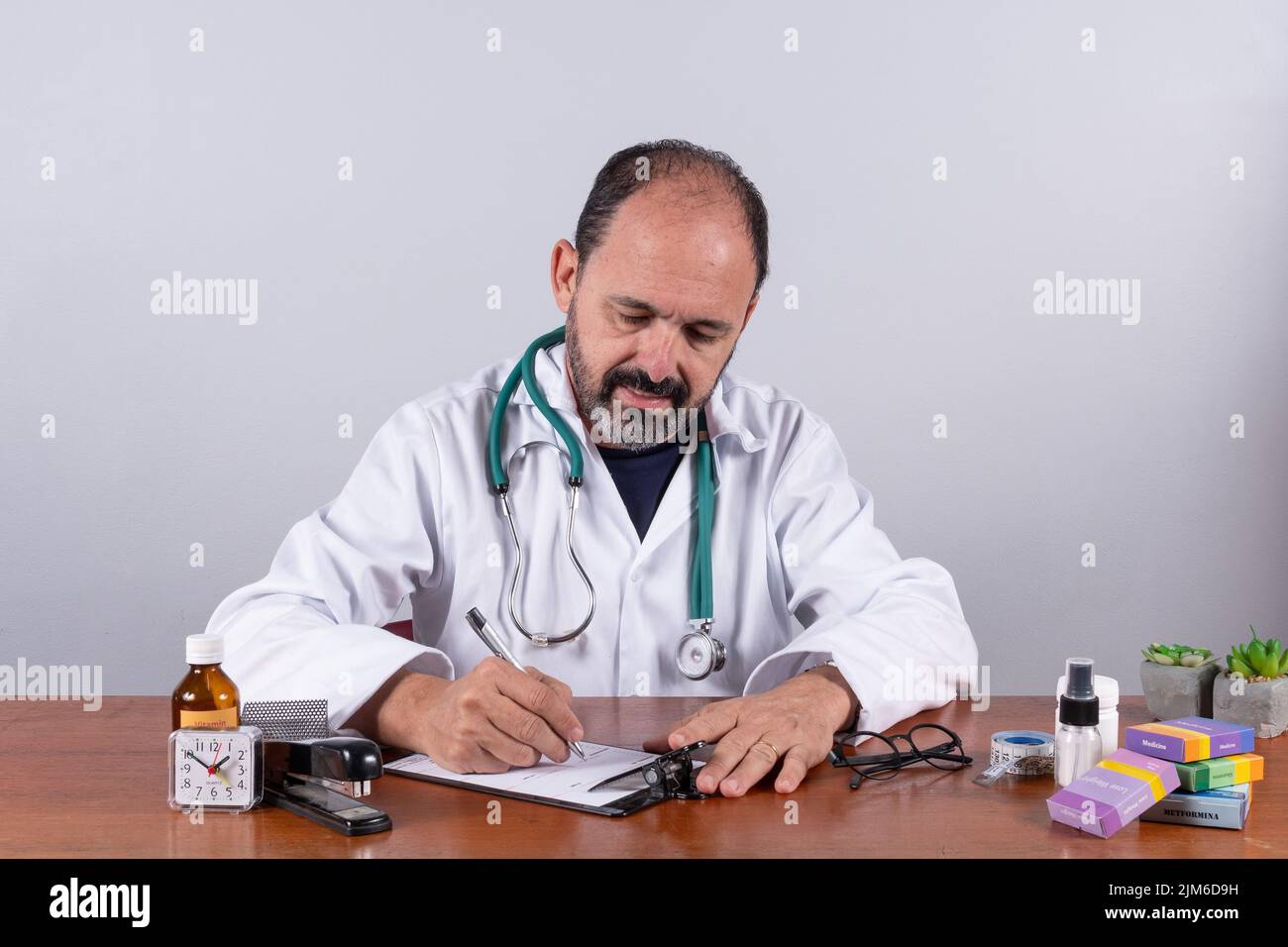 Portrait d'un médecin mature senior écrivant sur ordonnance regardant vers le bas Banque D'Images