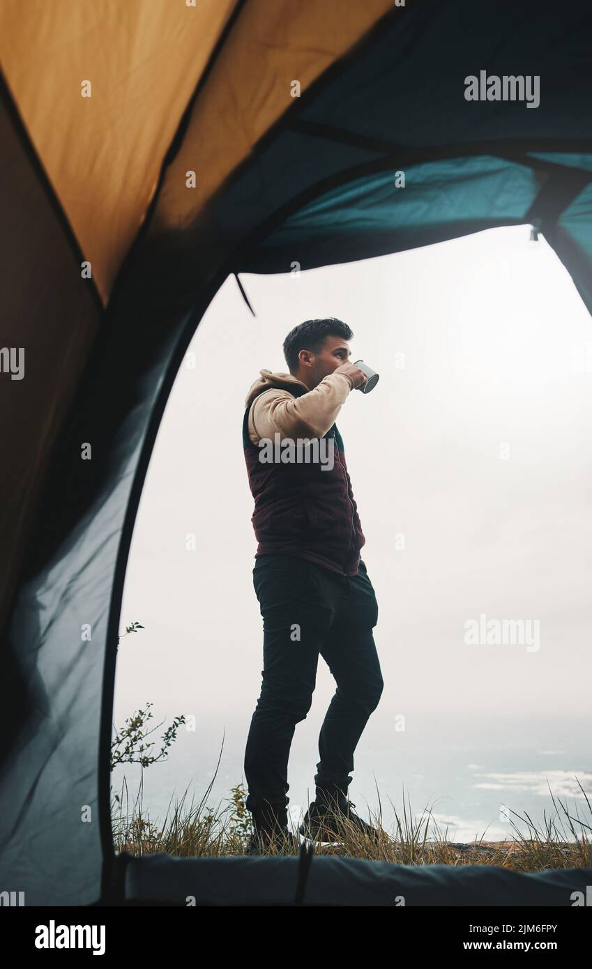 La nature est beaucoup moins chère que la thérapie. Un jeune homme qui boit du café tout en campant dans le désert. Banque D'Images