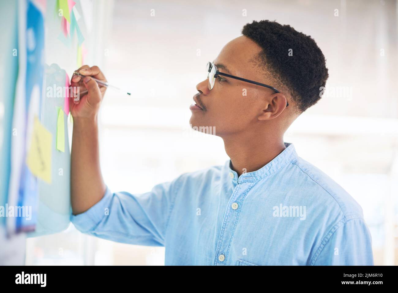 Le plus petit détail peut déterminer votre direction. Un jeune homme d'affaires ayant une session de brainstorming dans un bureau moderne. Banque D'Images