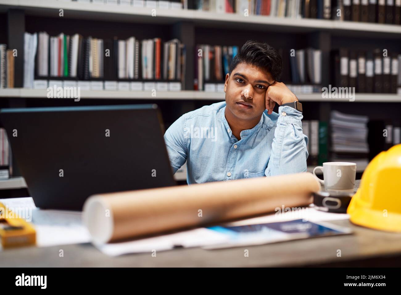 Je pense que ma carrière a une crise de milieu de vie. Portrait d'un jeune architecte regardant s'ennuyer tout en travaillant à son bureau dans un bureau moderne. Banque D'Images