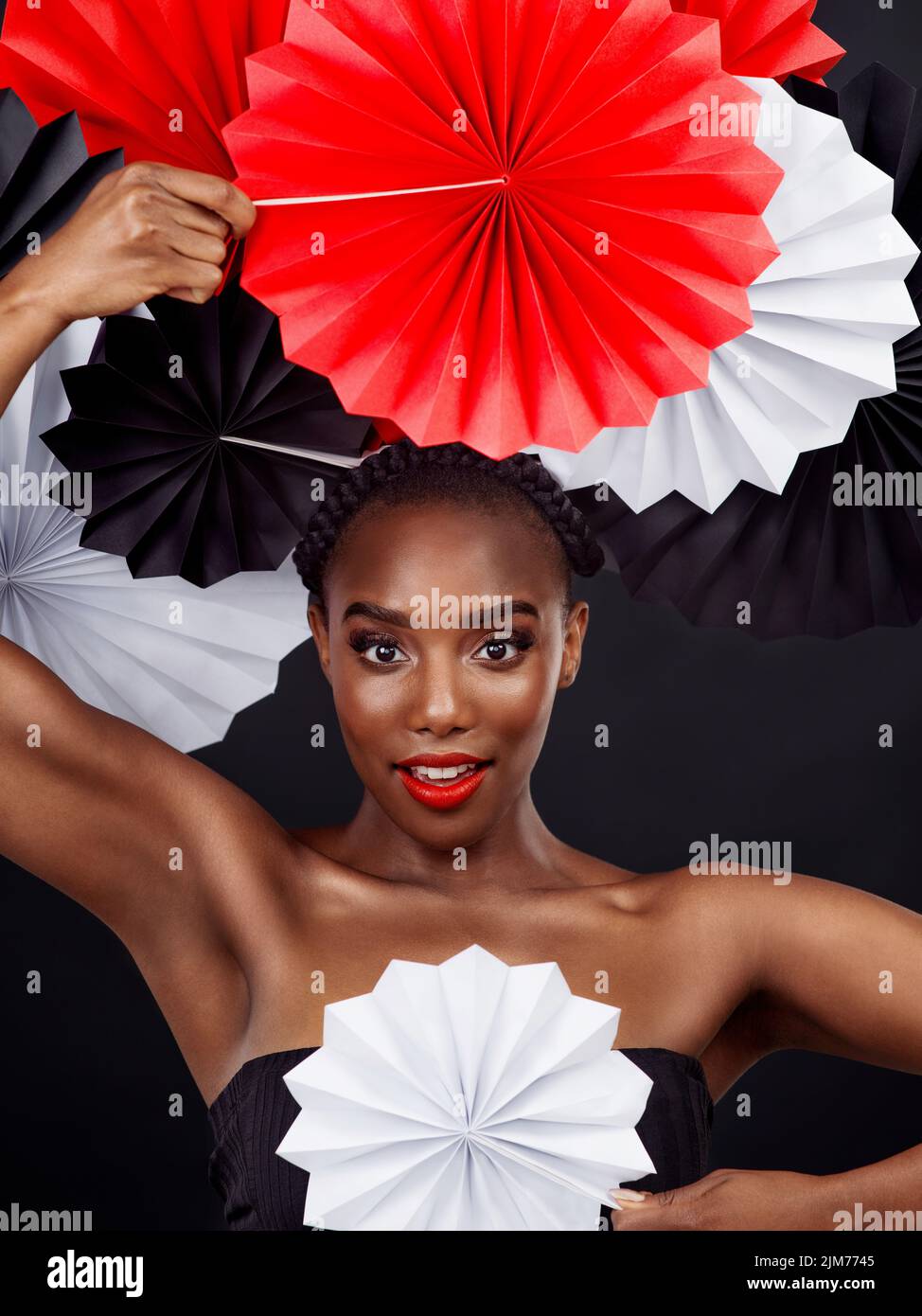 Tisser différentes cultures dans un seul regard glorieux. Photo studio d'une belle jeune femme posant avec un ventilateur origami sur un fond noir. Banque D'Images