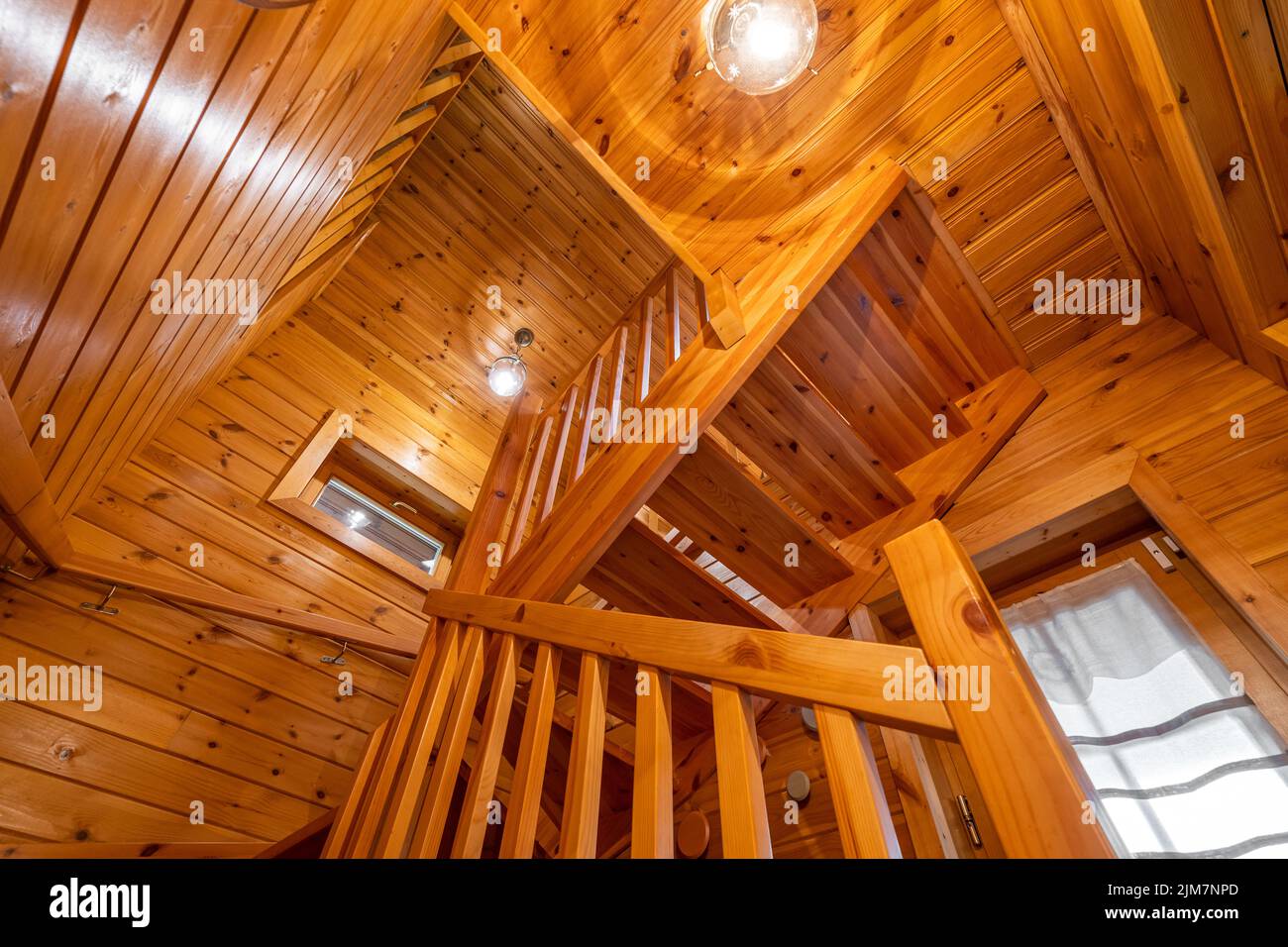 Vue de bas en haut d'un escalier en bois avec garde-corps dans une maison de campagne. Atmosphère chaleureuse de la maison de campagne Banque D'Images