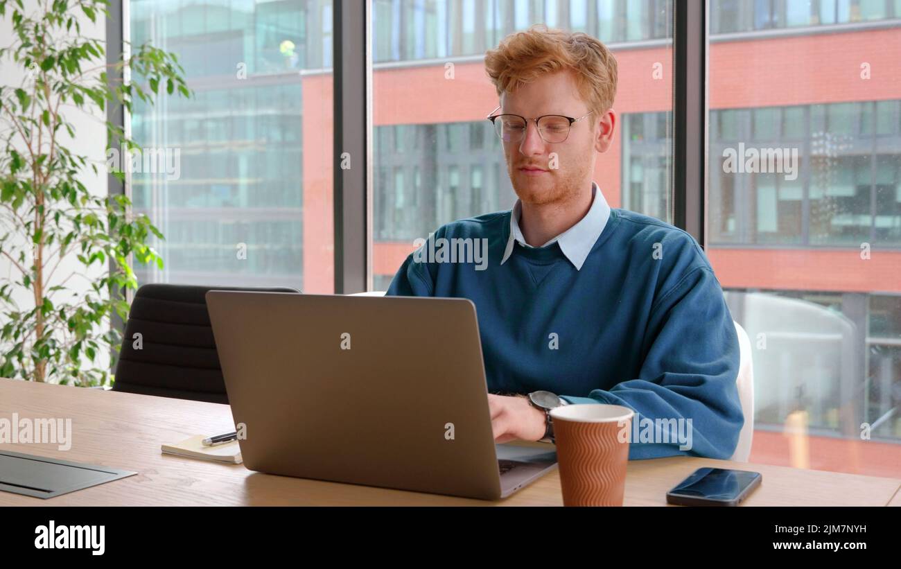 Un jeune homme d'affaires plein de confiance travaille en ligne sur son lieu de travail, sur un ordinateur portable au bureau. Banque D'Images