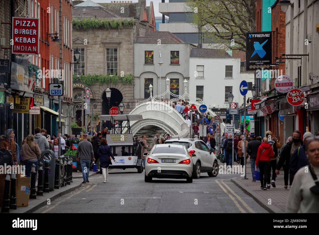 En regardant la rue Liffey Lower avec Ha'penny Bridge à la fin. Les gens marchent sur les trottoirs. Rue animée dans le centre-ville de Dublin. Banque D'Images
