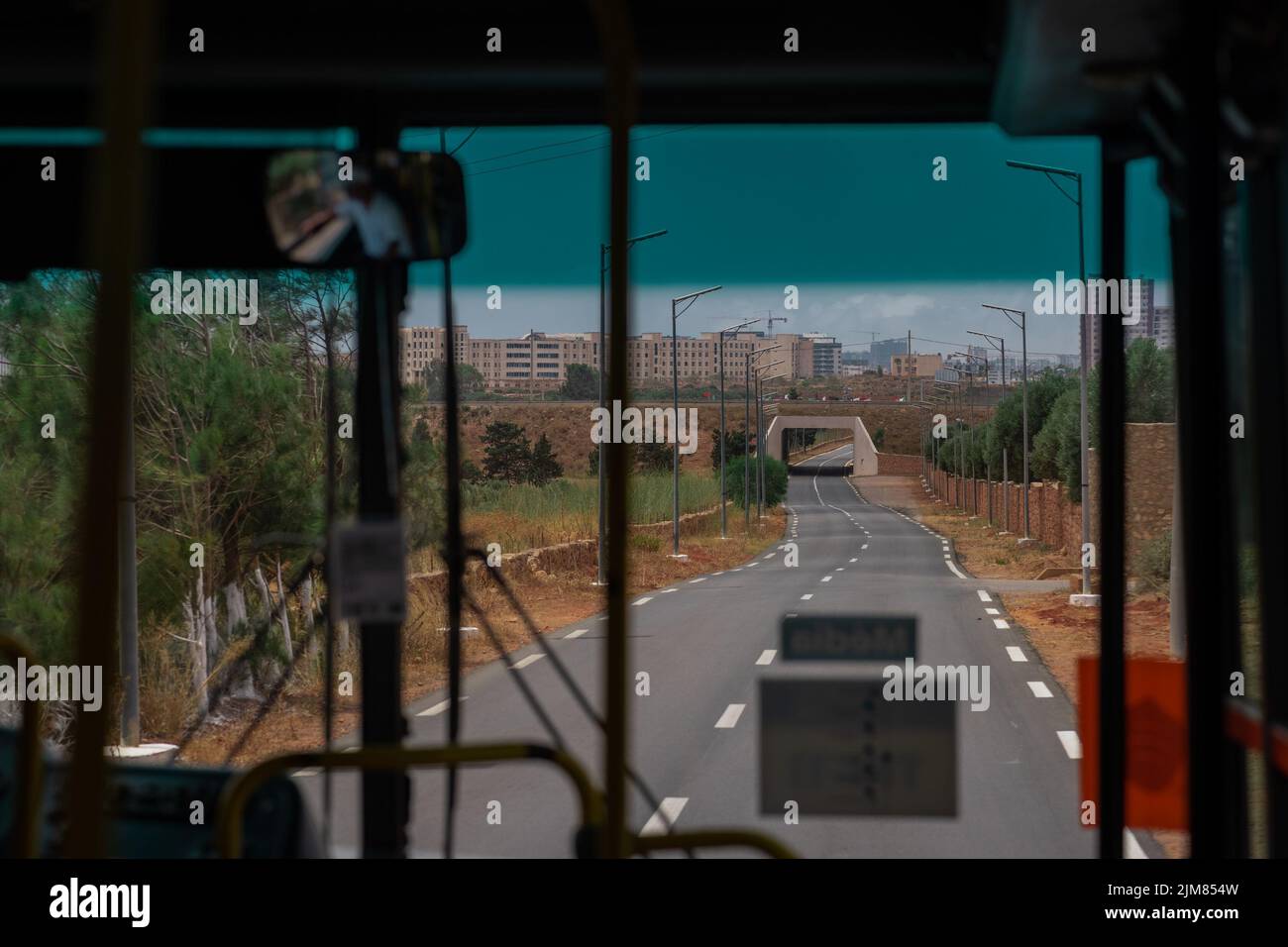 Conduite avec un bus public sur une route en direction de la ville d'Oran, Algérie. Vue à travers la fenêtre de bus vers le passage inférieur de l'autoroute. Banque D'Images