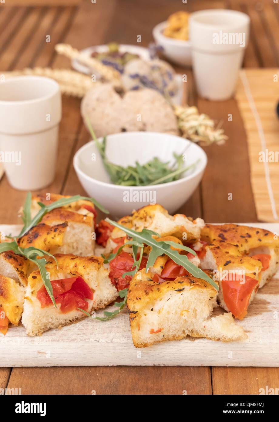 Focaccia italien d'apéritif d'été avec tomates cerises et rucola servi à l'extérieur avec des verres de vin rouge. Pain sec typique des Pouilles, fait à Salen Banque D'Images