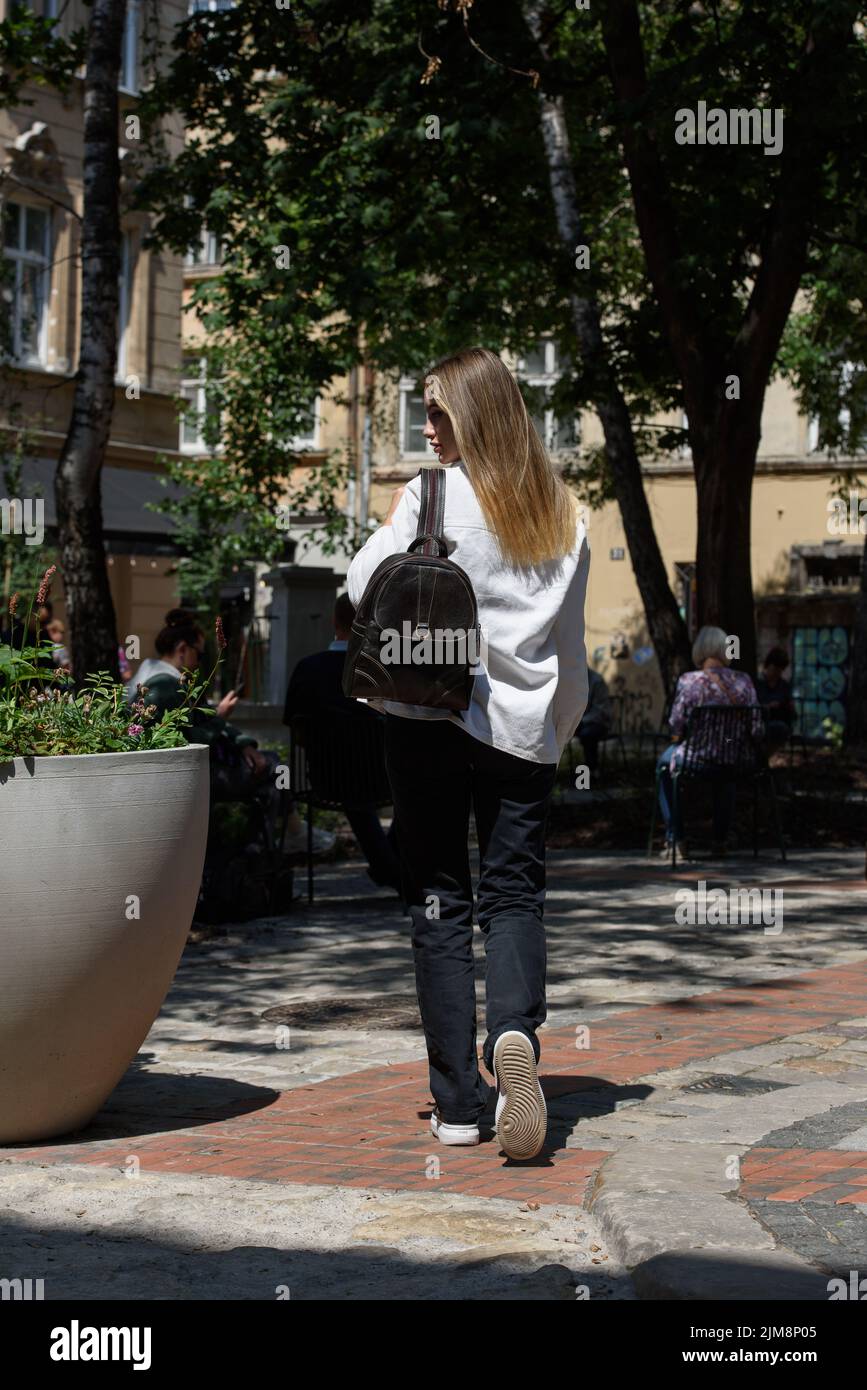 photo d'une femme avec un sac à dos en cuir marron avec un look ancien et rétro. Photo à l'extérieur. Vue arrière Banque D'Images