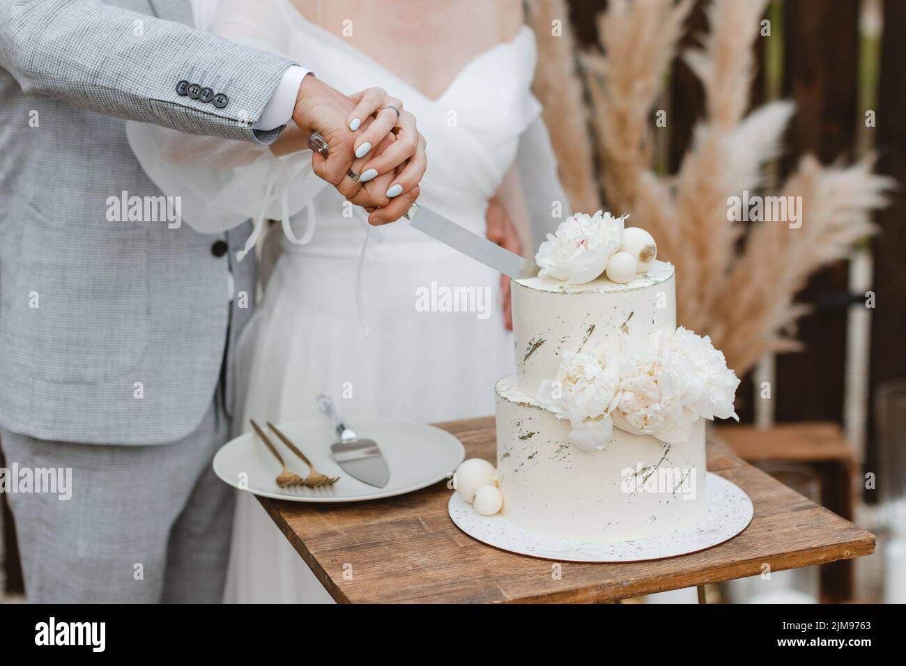 Mariage à l'extérieur, mariage avec mariage, coupe de gâteau de mariage élégant et marié. Mariage couple tenant couteau et coupant ensemble gâteau de mariage décoré avec flux Banque D'Images