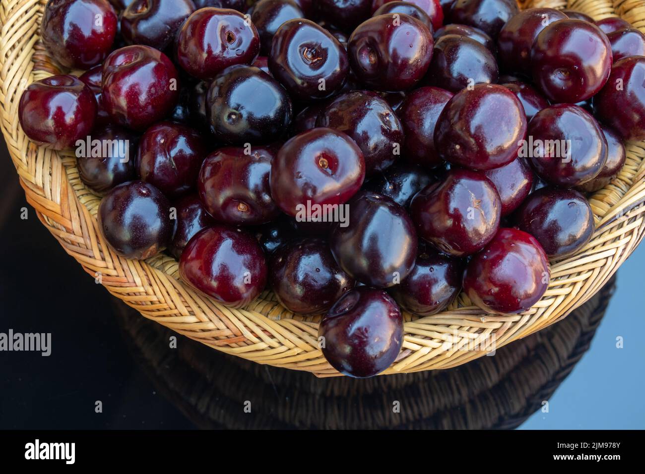 Gros plan de cerises mûres fraîches , dans un panier en osier coloré de cerises mûres fraîches , dans un panier en osier coloré Banque D'Images