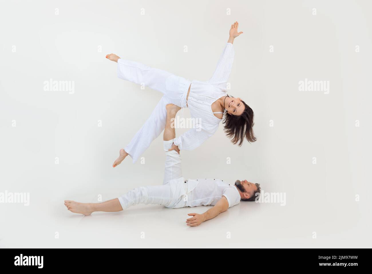 Active, sportive famille heureuse d'homme et de femme pratiquant le yoga en couple. Homme tenir la femme côté comme une étoile dans l'air sur la jambe. Banque D'Images