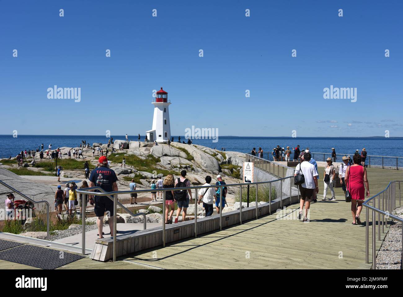 Peggy’s Cove, Canada - 31 juillet 2022 : les gens voient le célèbre phare de Peggy’s Cove. Une plate-forme d'observation en bois a été installée en 2021 pour donner peopl Banque D'Images
