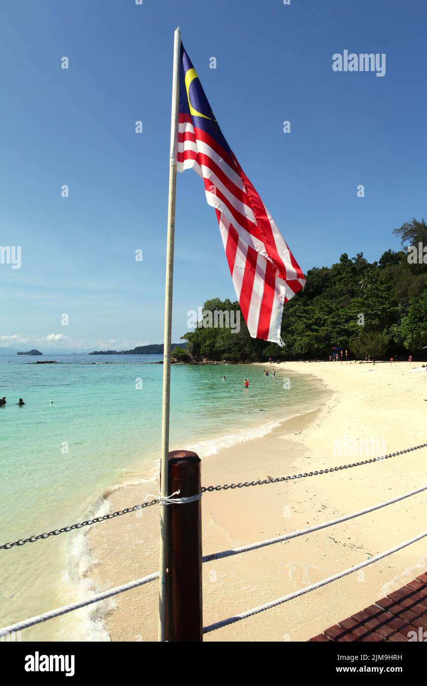 Drapeau national de la Malaisie en arrière-plan d'une plage sur Pulau SAPI (île SAPI), une partie du parc Tunku Abdul Rahman à Sabah, en Malaisie. Banque D'Images