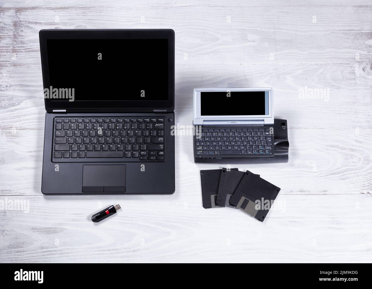 Ordinateur ancien et moderne avec périphériques de stockage de données sur un arrière-plan de bureau blanc Banque D'Images