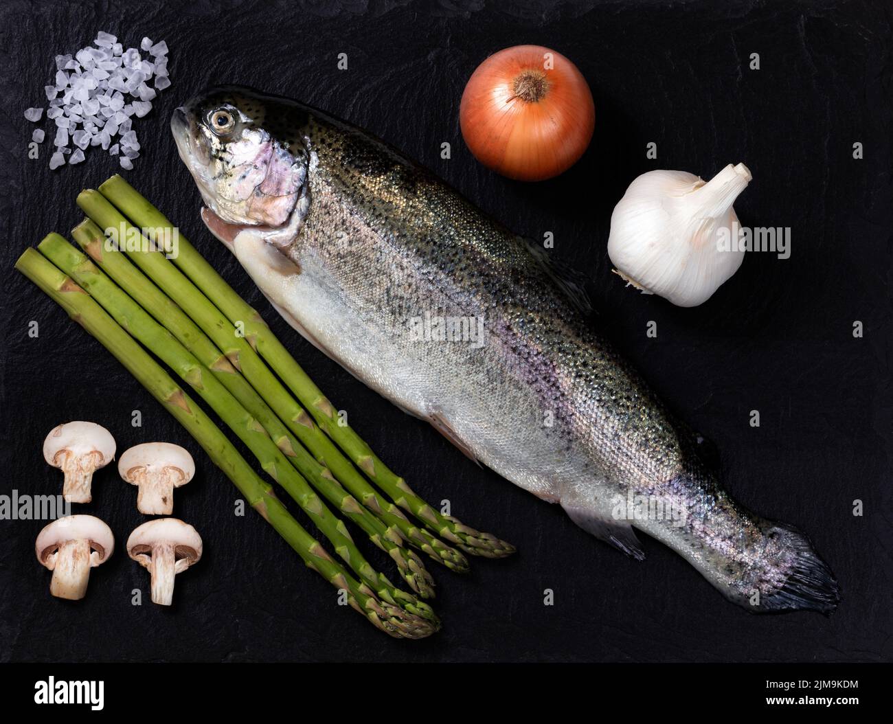 Cru poisson entier avec des légumes et des épices sur fond de pierre d'ardoise naturelle Banque D'Images
