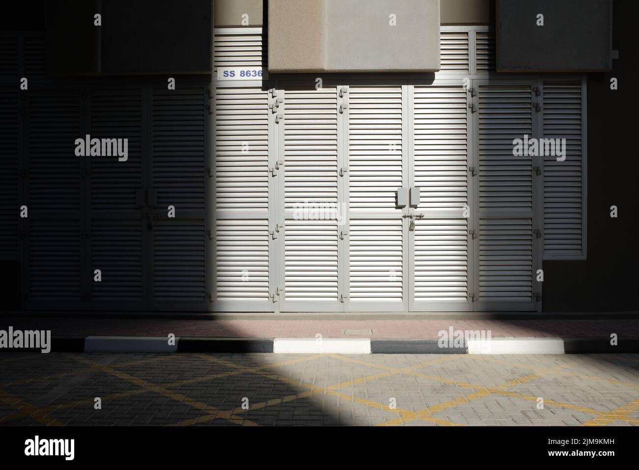 Un fragment de lumière du soleil touche des portes à persiennes en aluminium gris à l'extérieur d'un bâtiment urbain à Dubaï, aux Émirats arabes Unis. Banque D'Images