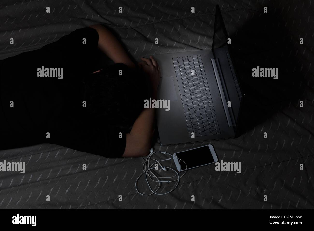 Une jeune fille s'endorme en utilisant un ordinateur portable pendant son coucher Banque D'Images