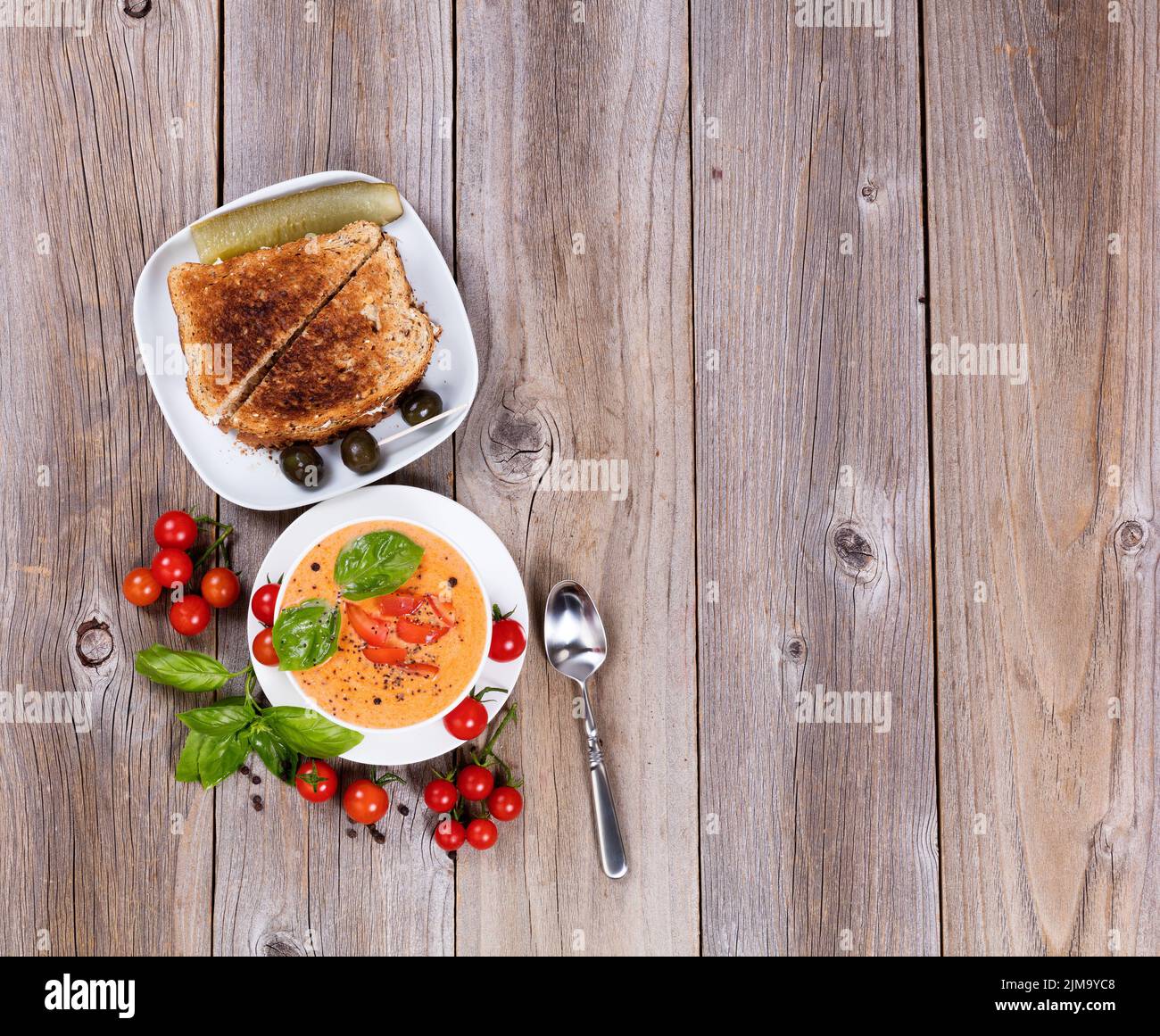 Soupe de tomates crémeuse et fraîche et sandwich aux feuilles de basilic sur des planches de bois rustiques Banque D'Images