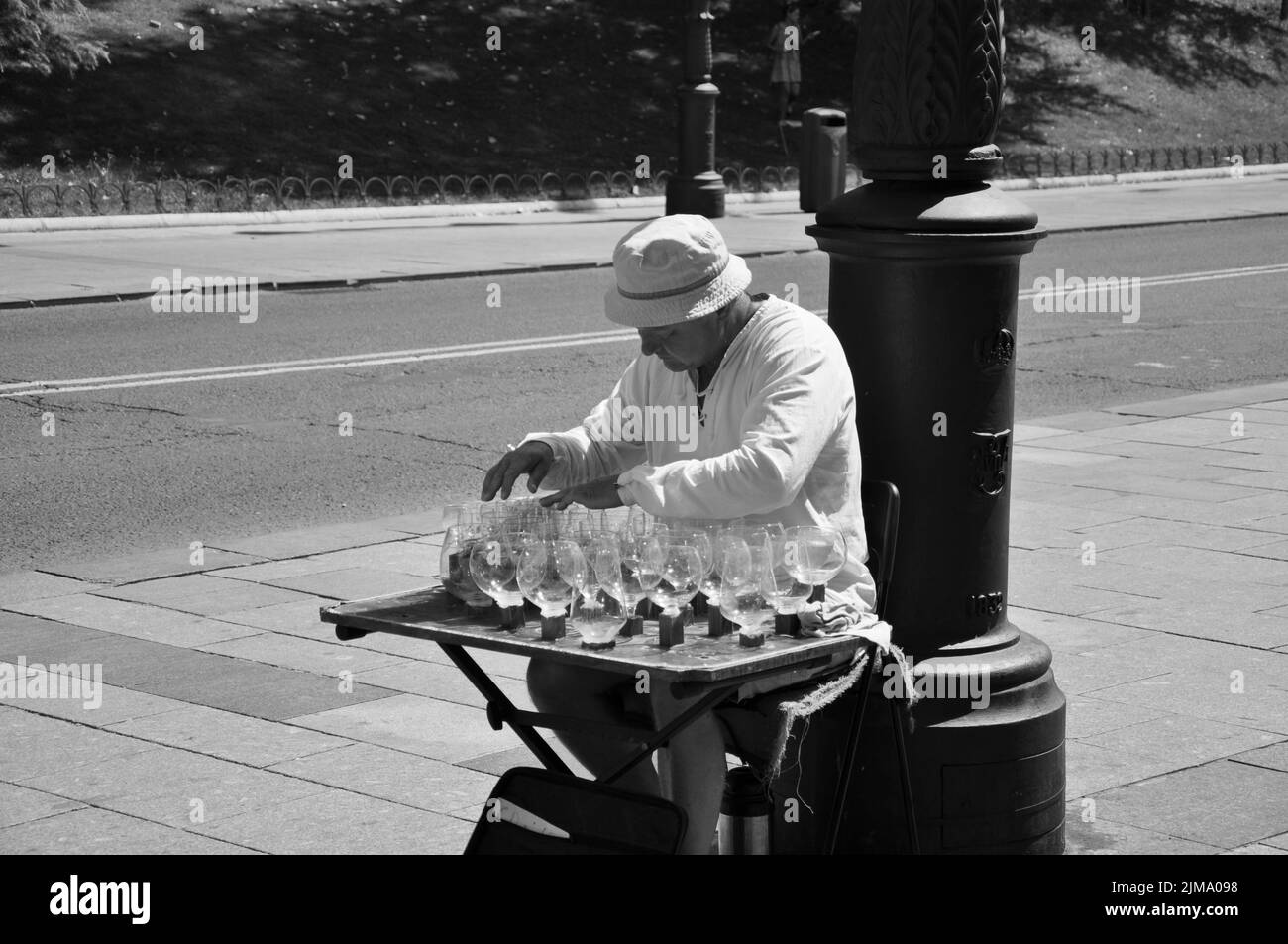 Un homme dans un chapeau blanc jouant de la musique dans des verres à vin Banque D'Images