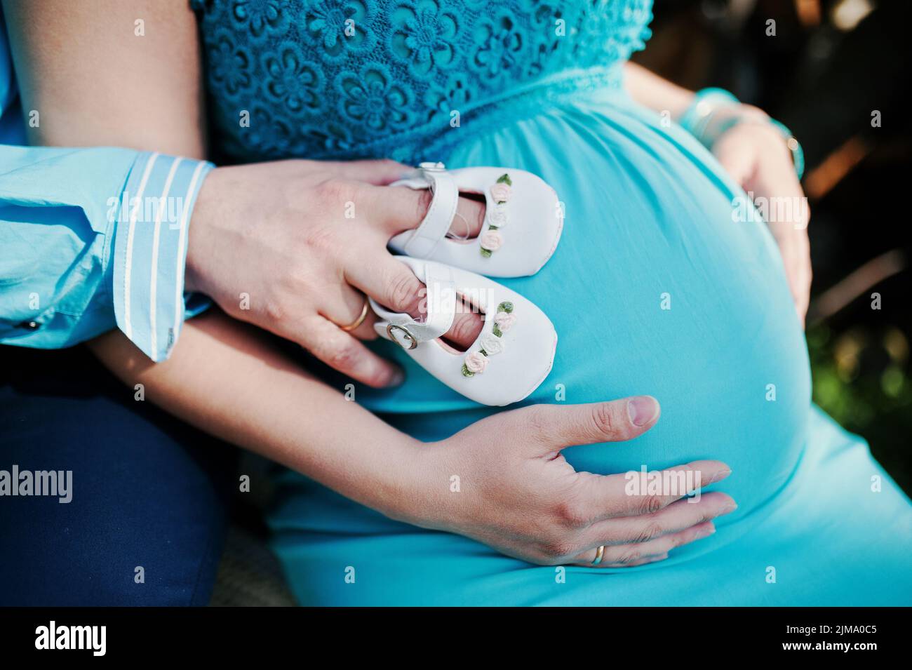 Femme enceinte et son mari se tenant la main sur le ventre avec des filles Chaussures de bébé. Nouveau thème vie Banque D'Images