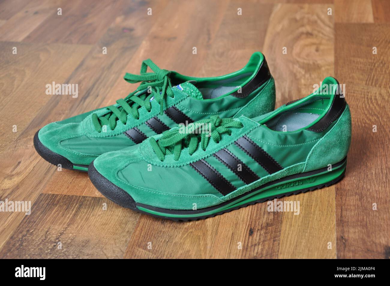 Un gros plan des sneakers vertes Adidas rétro pour coureurs. Banque D'Images
